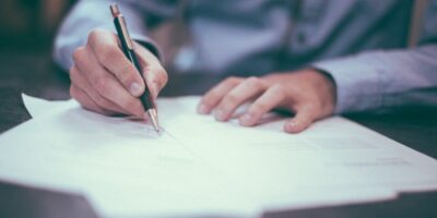 Man writing on paperwork dealing with an insurance claim